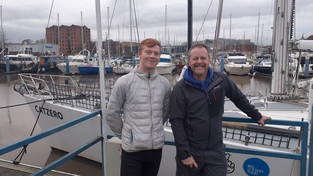 Two people standing in front of a boat at a marina