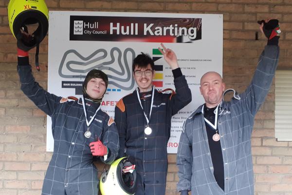 Three people celebrating at karting track